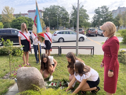 Uczennice składają kwiaty przed Dębem Pamięci.