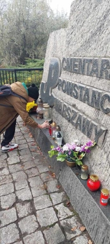 Uczeń zapala znicz przy pomniku Powstańców Warszawy na cmentarzu