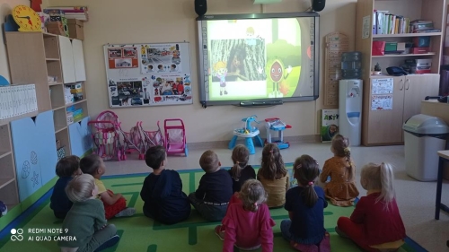 Przedszkolaki oglądają film edukacyjny o jesieni. 