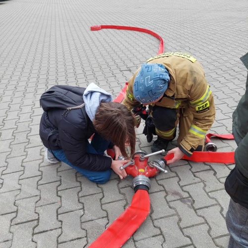 Uczeń ze strażakiem podpinają wąż gaśniczy